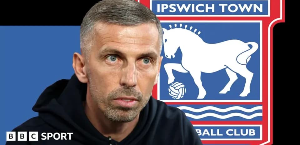 Entrenador hablando con logo de Ipswich Town detrás