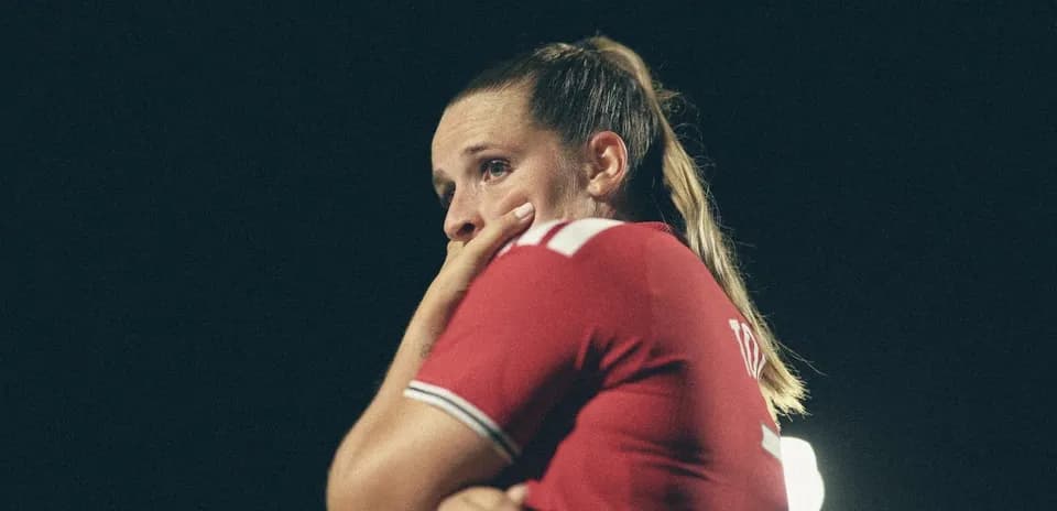 Jugadora de fútbol con camiseta roja pensativa