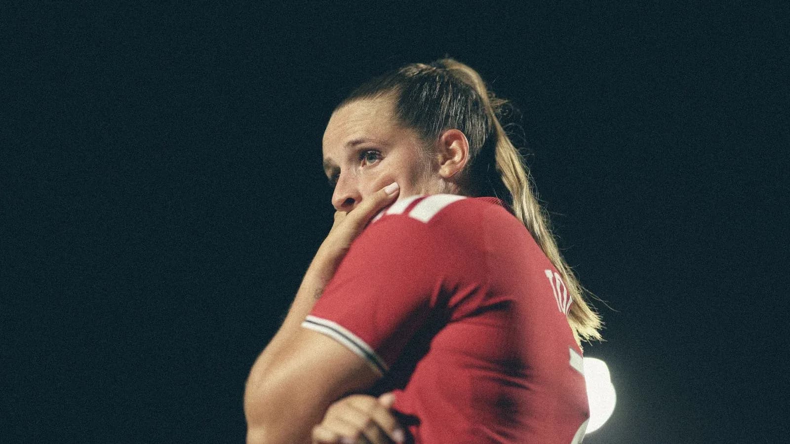 Jugadora de fútbol con camiseta roja pensativa
