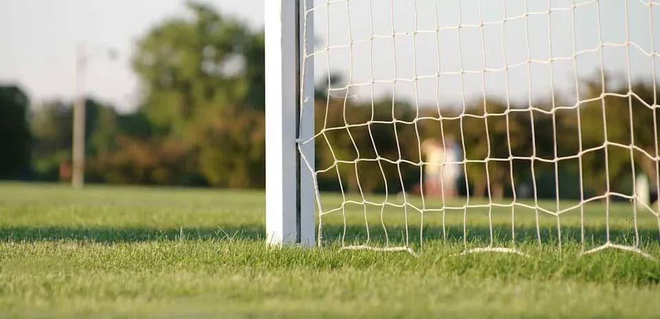 Portería de fútbol en campo verde al atardecer