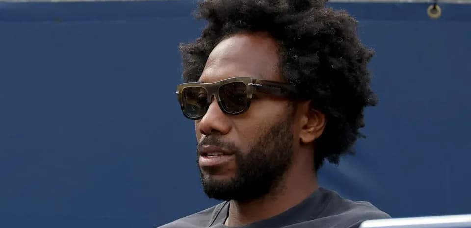 Hombre con gafas oscuras sentado en tribuna