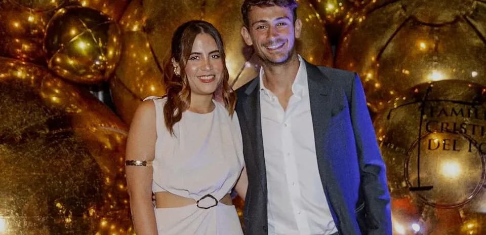 Pareja posando frente a globos dorados en evento