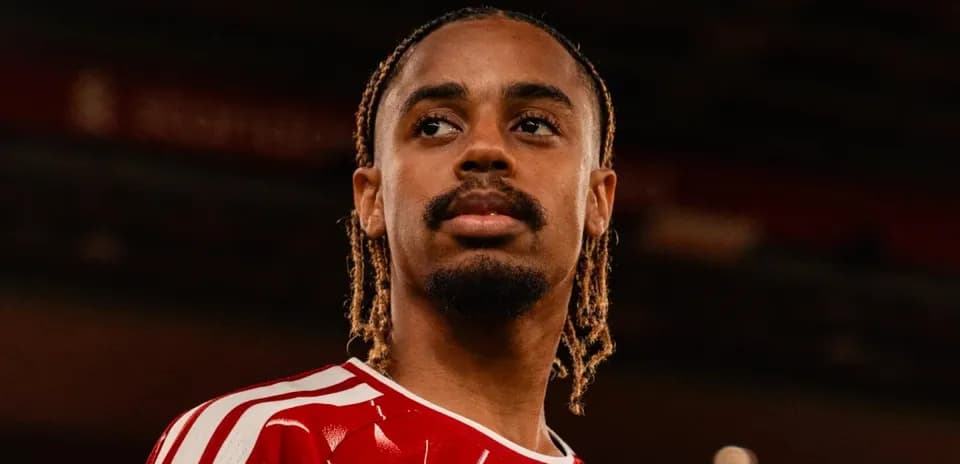 Jugador con camiseta roja posando en el estadio