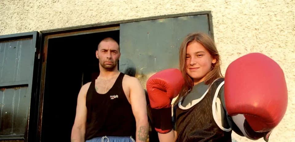 Niña boxeadora con guantes junto a un hombre