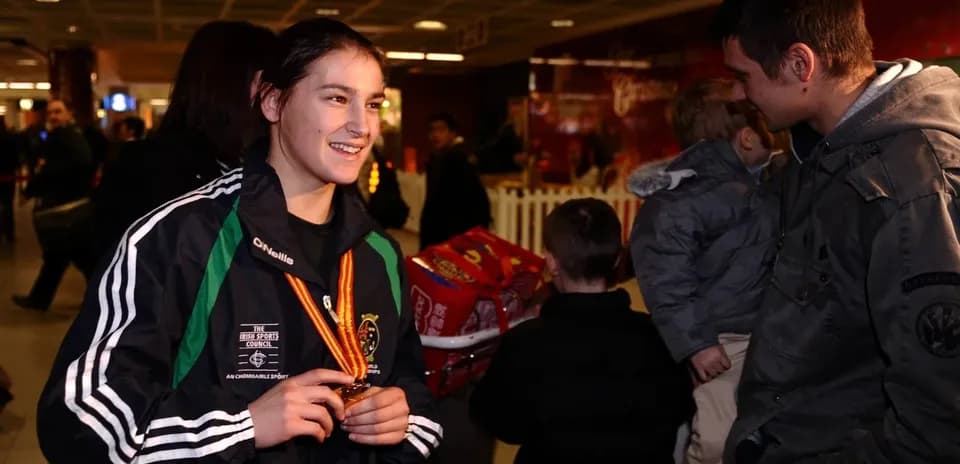 Atleta sonriente con medalla en el aeropuerto