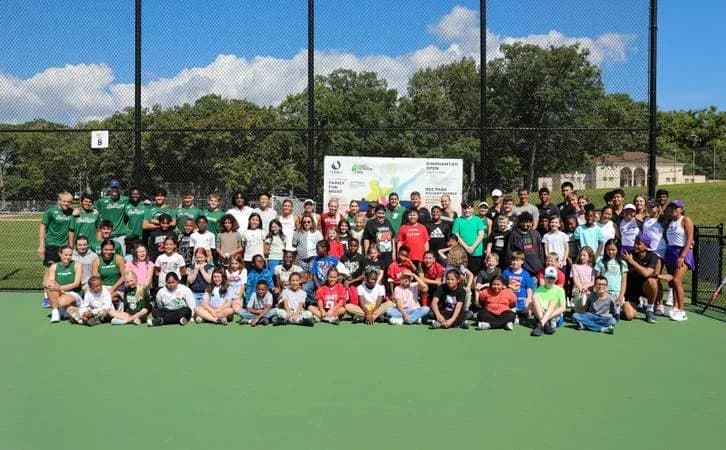Grupo grande de personas en cancha de tenis