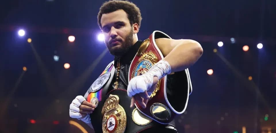 Boxeador mostrando cinturones en el ring