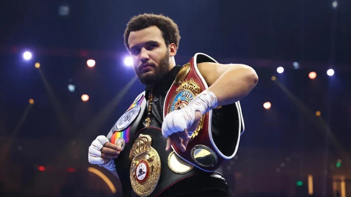 Boxeador mostrando cinturones en el ring