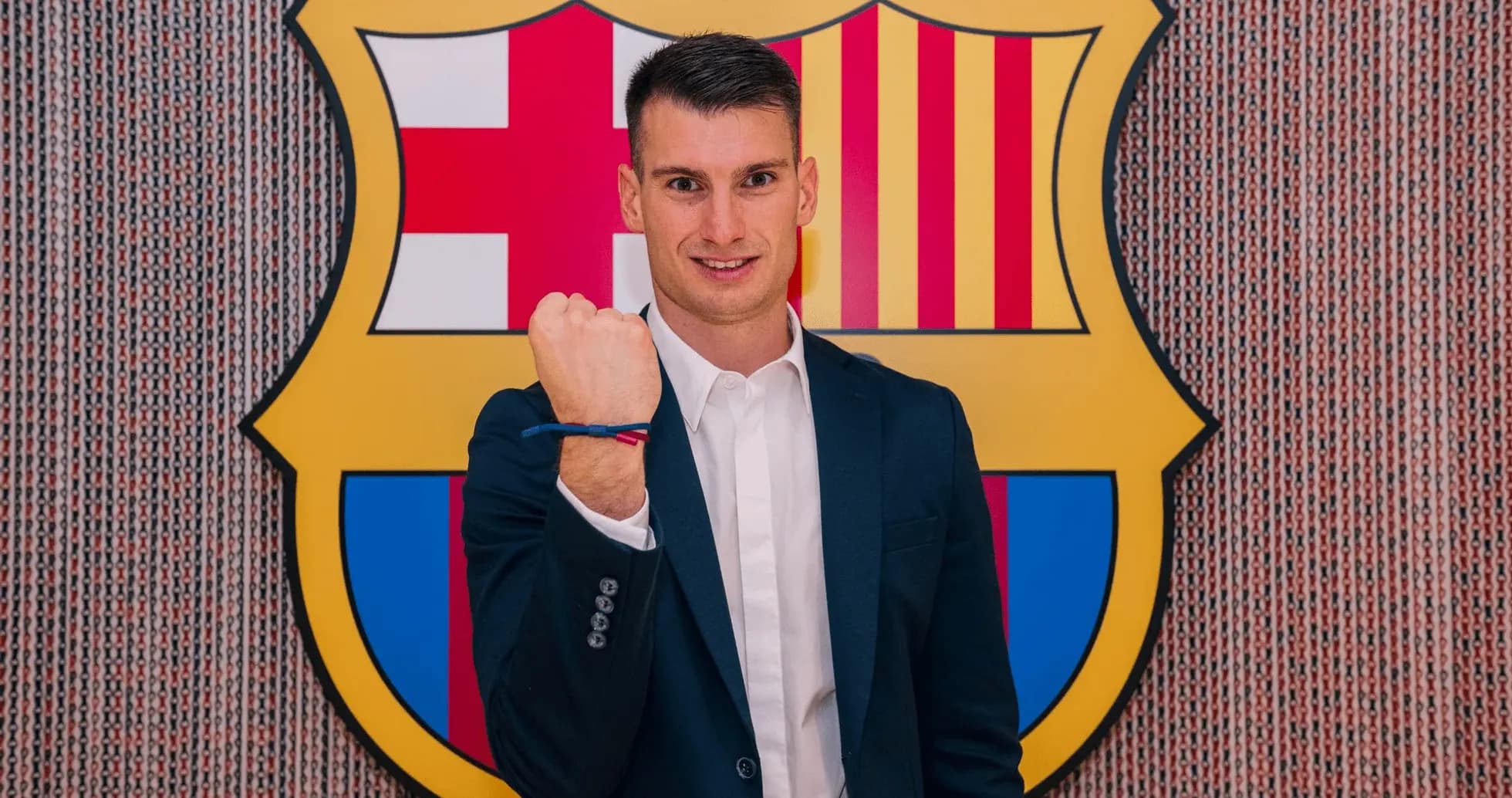 Jugador mostrando puño frente al escudo del Barcelona