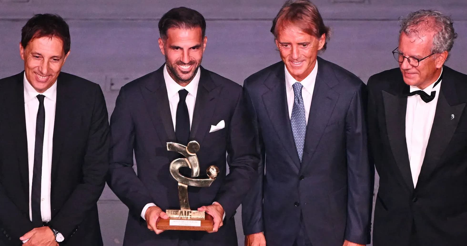 Cuatro personas posando con un trofeo en evento