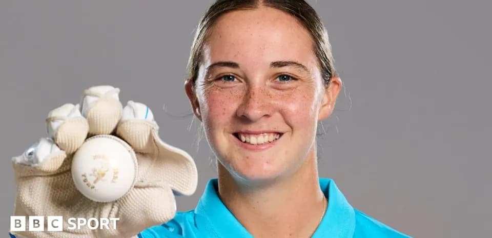 Jugadora de cricket sosteniendo una pelota sonriente