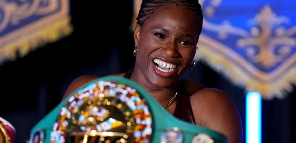 Boxeadora sosteniendo cinturón de campeona y sonriendo