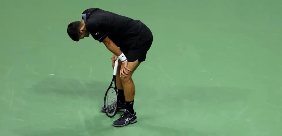 Jugador de tenis agachado sosteniendo su raqueta