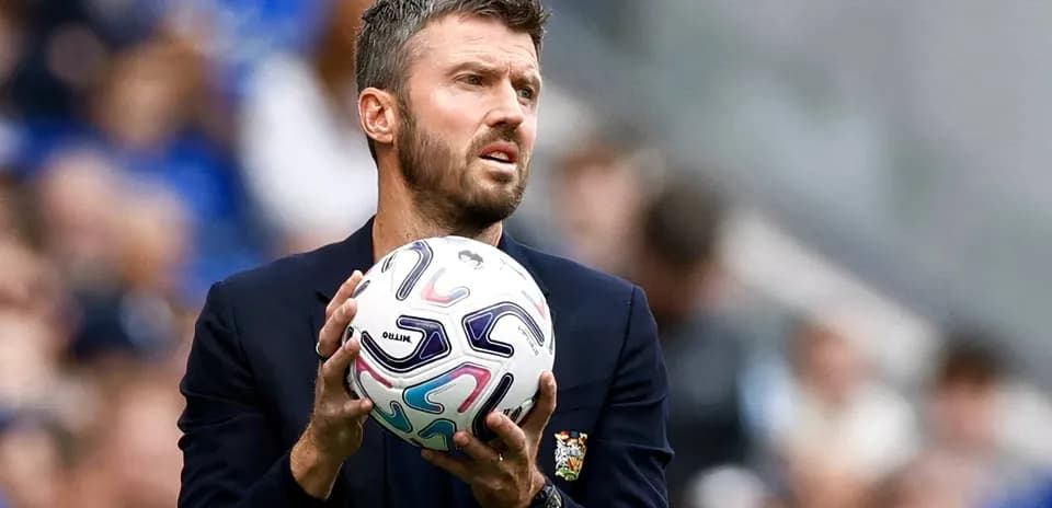 Entrenador sosteniendo un balón de fútbol en el campo