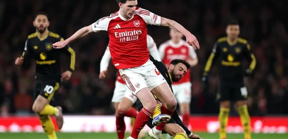 Jugador de Arsenal driblando mientras es tackleado