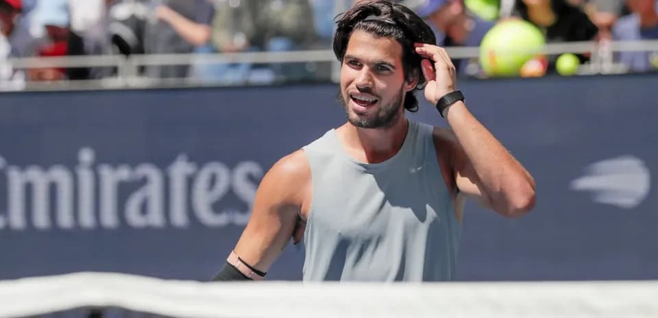 Jugador de tenis ajustando su cabello en la cancha
