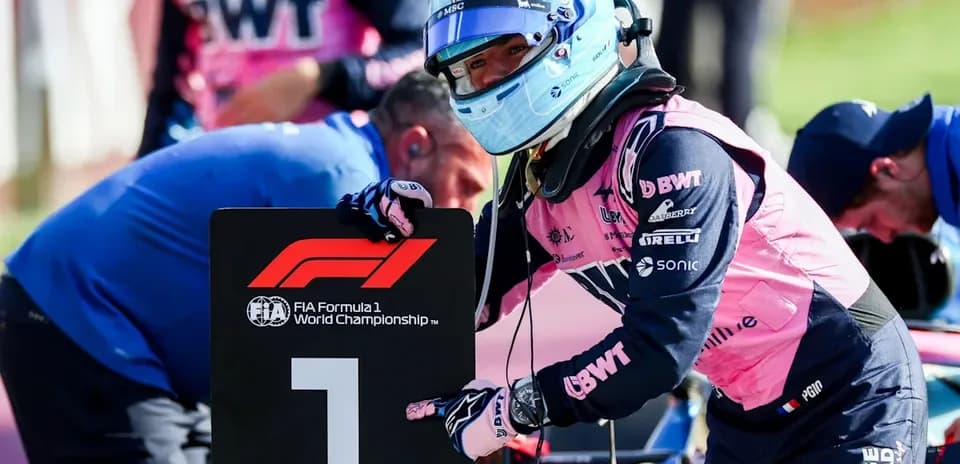 Piloto señalando el cartel número uno en carrera