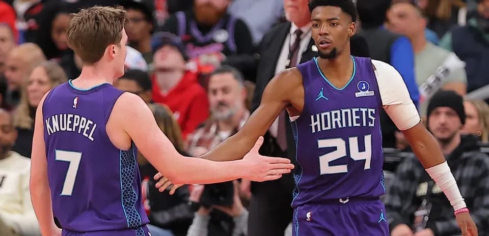 Jugadores de los Hornets chocando manos en partido