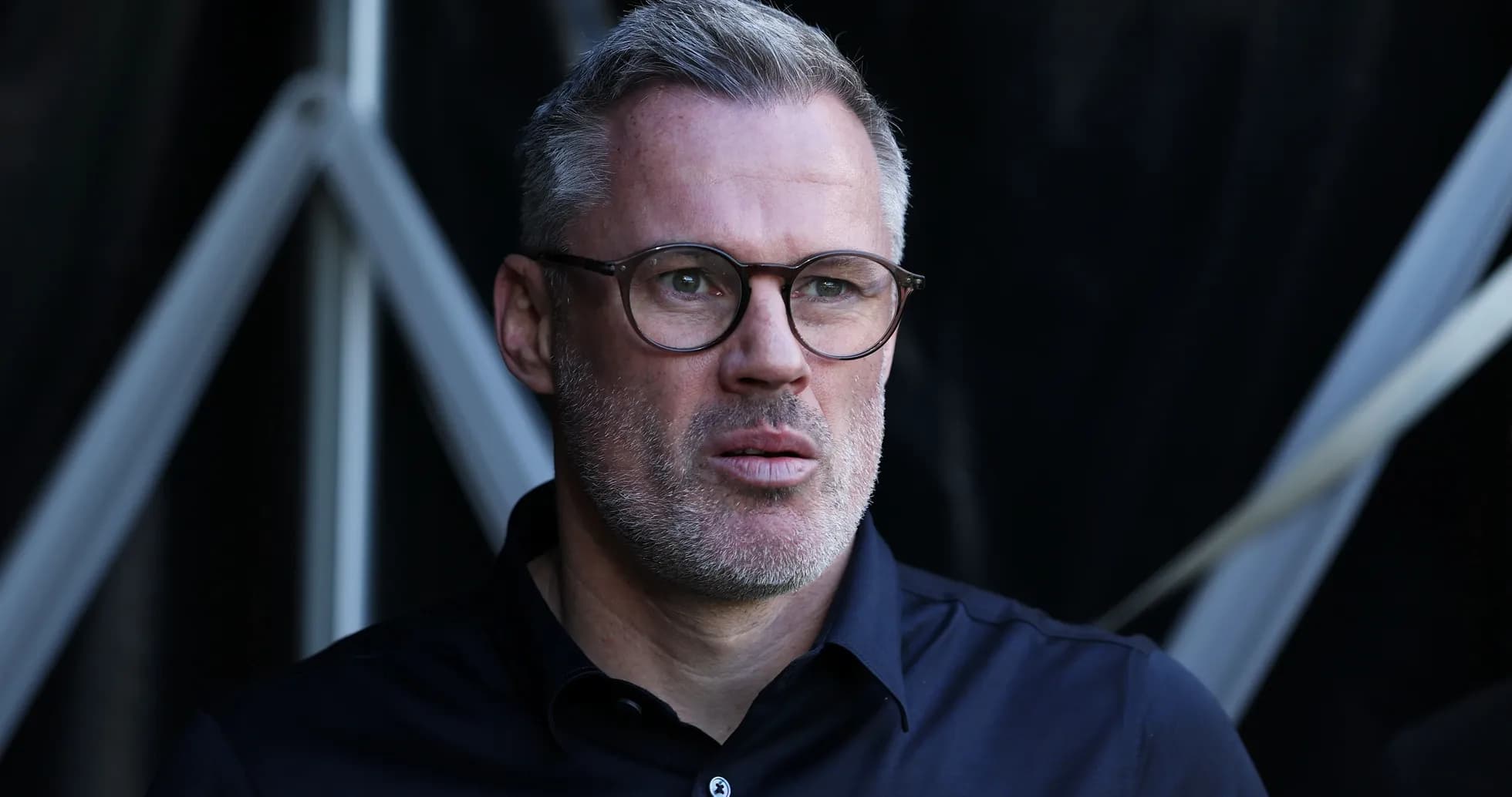 Hombre con gafas mirando hacia adelante en un fondo oscuro
