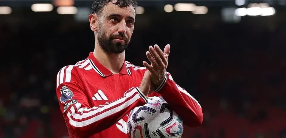 Jugador aplaudiendo con balón en mano en estadio