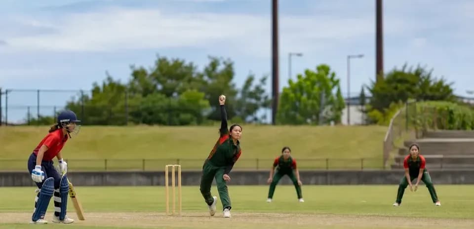 Jugadora lanzando en partido de cricket femenino