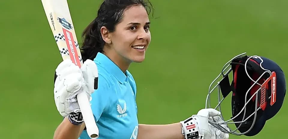 Jugadora de cricket levantando el bate tras anotar