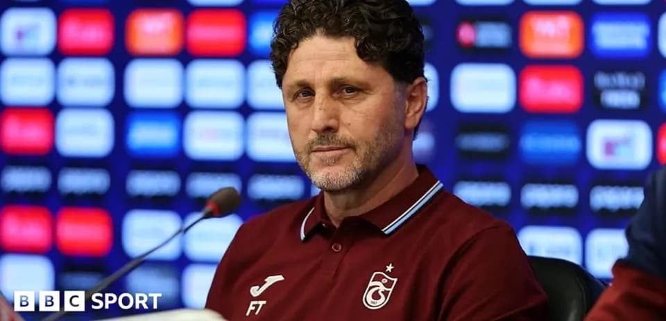 Entrenador en conferencia de prensa con fondo de logos
