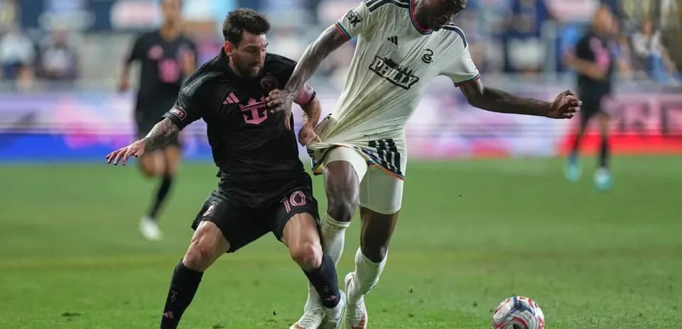 Lionel Messi and opponent contesting for the ball