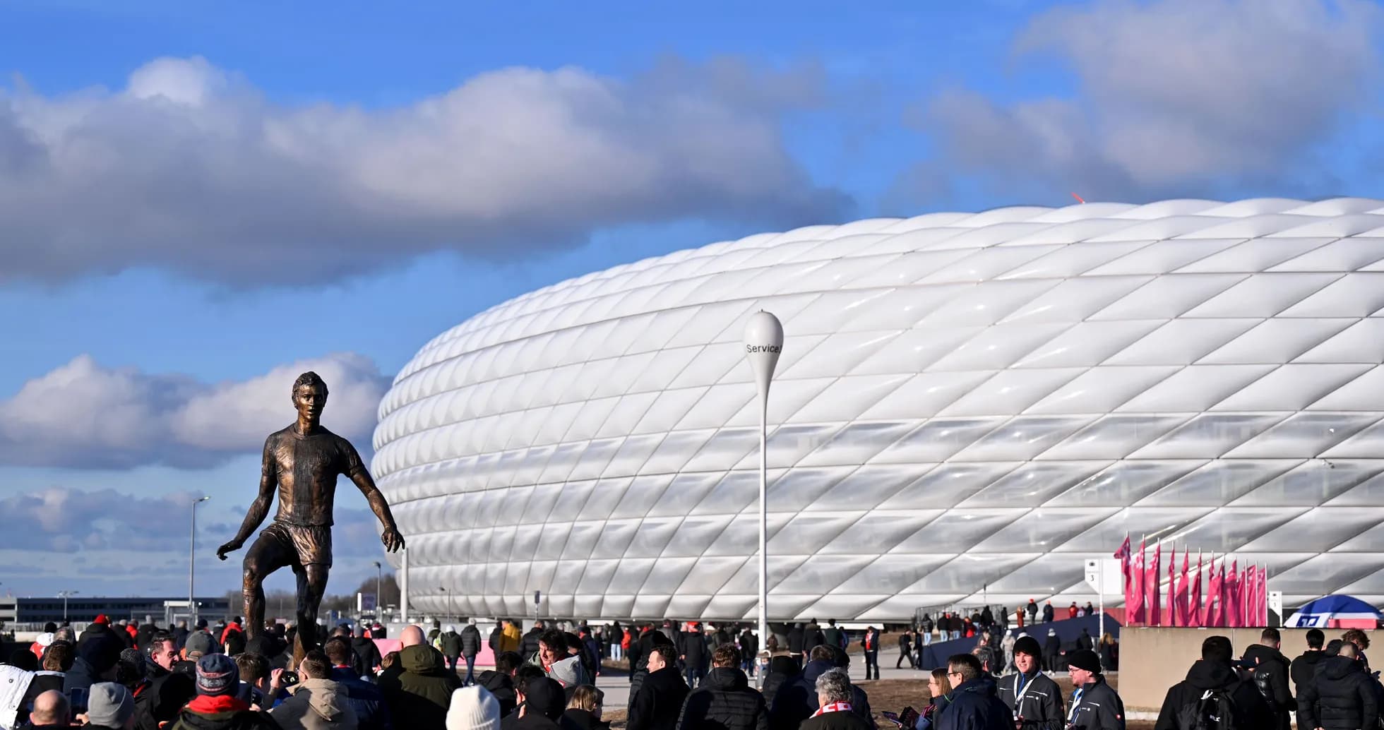 Estatua de jugador frente al Allianz Arena lleno de aficionados
