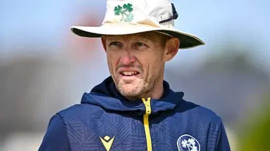 Entrenador de cricket con sombrero observando el campo