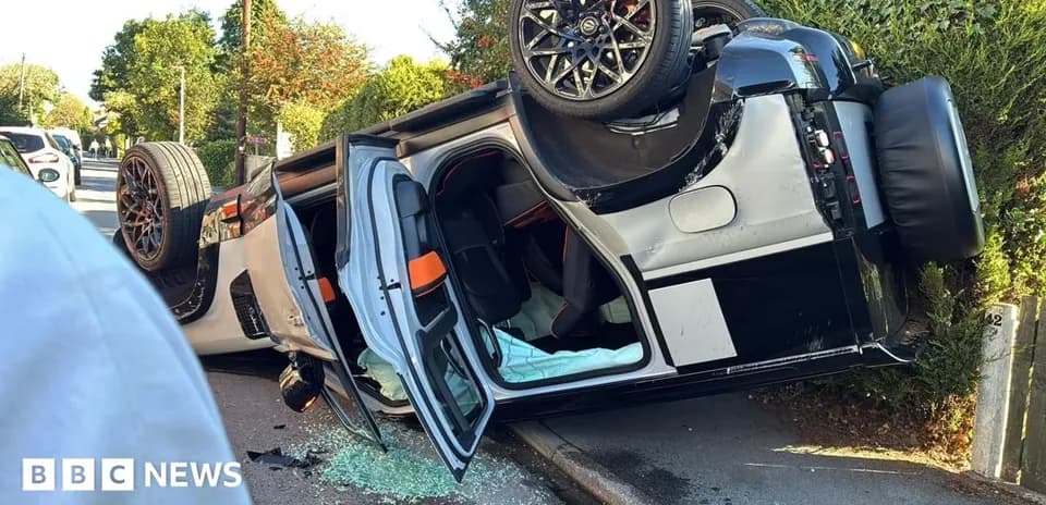 Coche volcado en la acera con cristales rotos