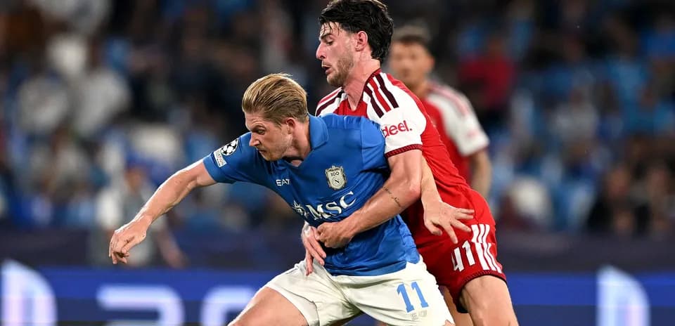 Jugador azul luchando por el balón contra oponente rojo