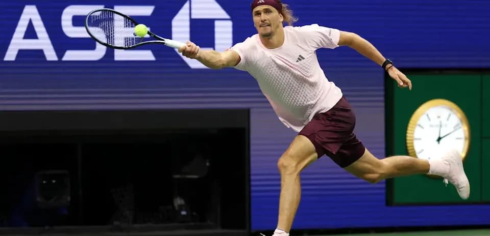 Jugador de tenis alcanzando una pelota en la cancha