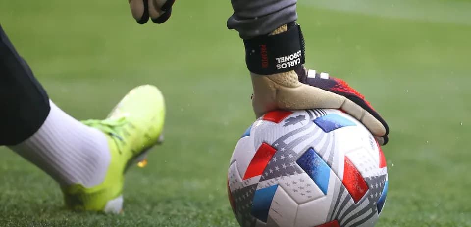 Portero sosteniendo un balón de fútbol en el campo