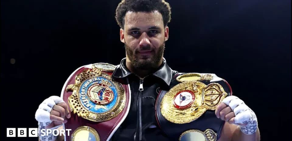 Boxeador sosteniendo cinturones de campeonato en ring