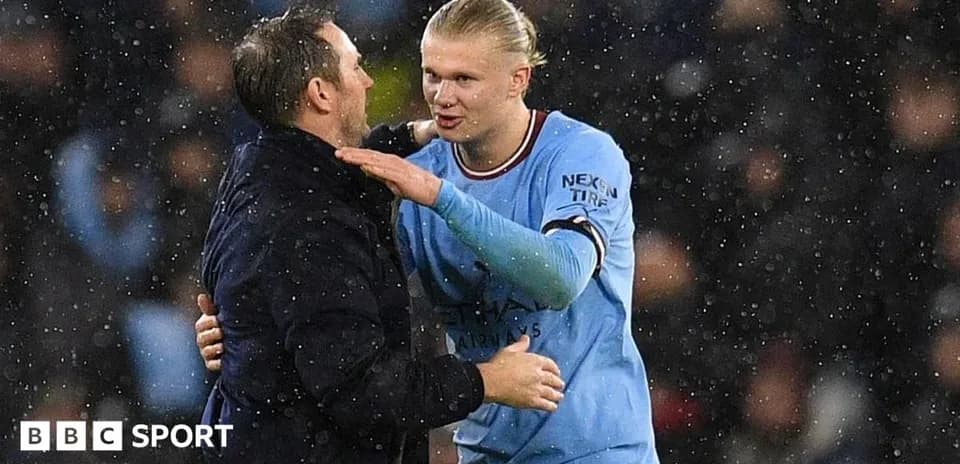 Entrenador y jugador de Manchester City conversando en lluvia