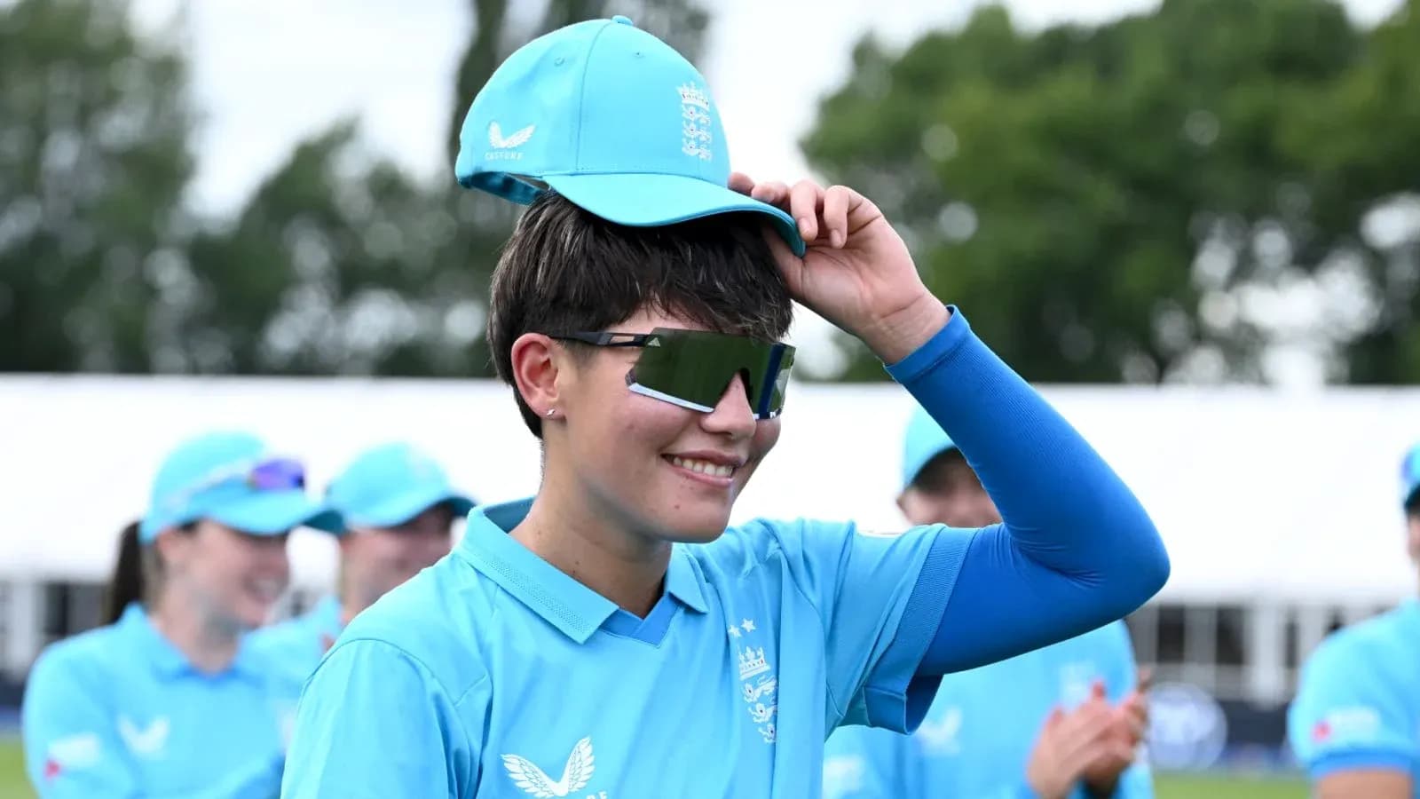 Jugadora de cricket con gorra y gafas de sol Jugadora de cricket con gorra y gafas de sol