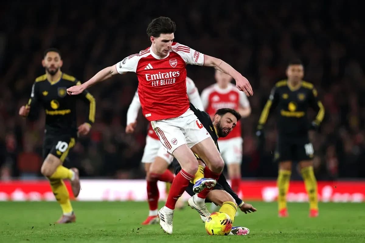 Jugador de Arsenal driblando mientras es tackleado Jugador de Arsenal driblando mientras es tackleado