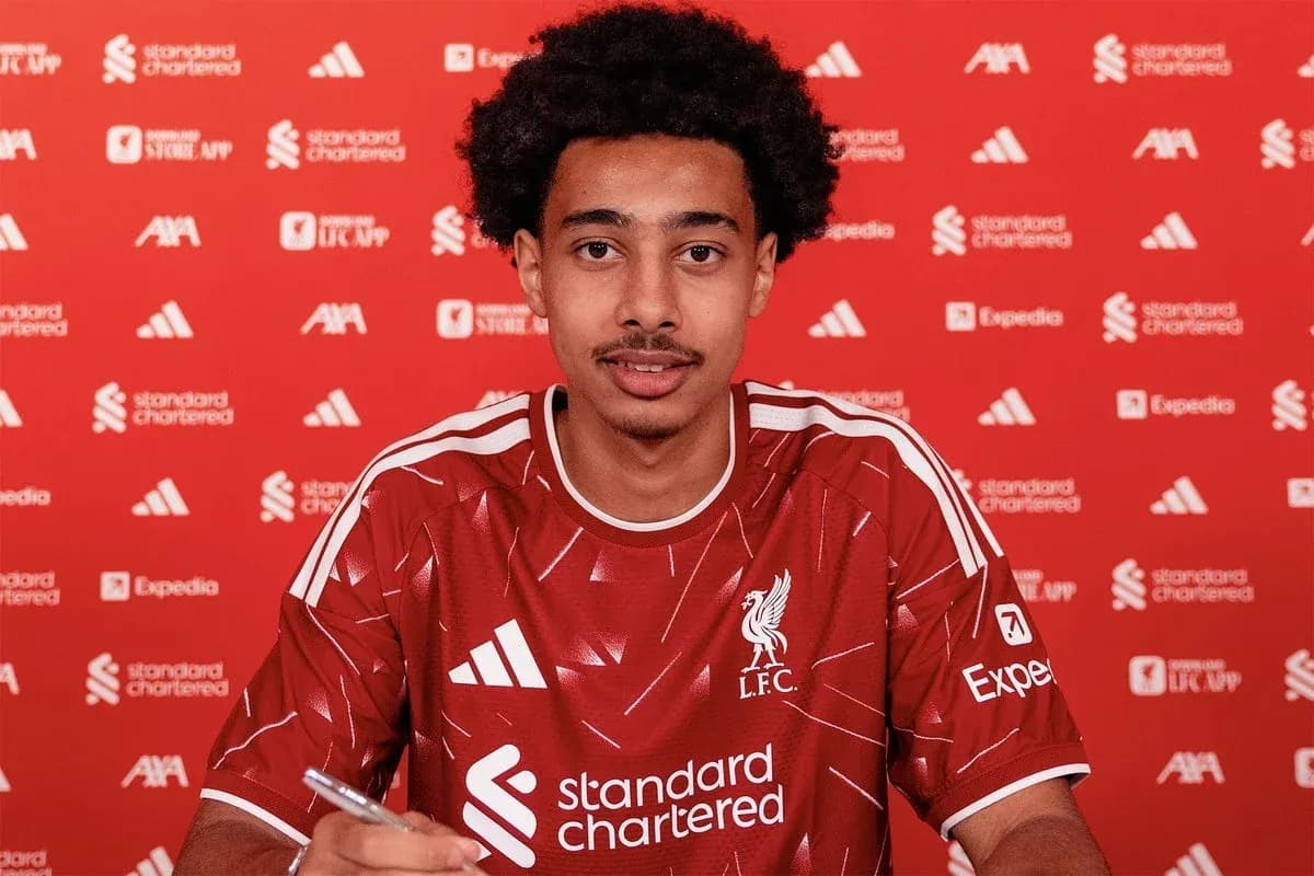 Jugador de Liverpool firmando contrato en mesa Jugador de Liverpool firmando contrato en mesa