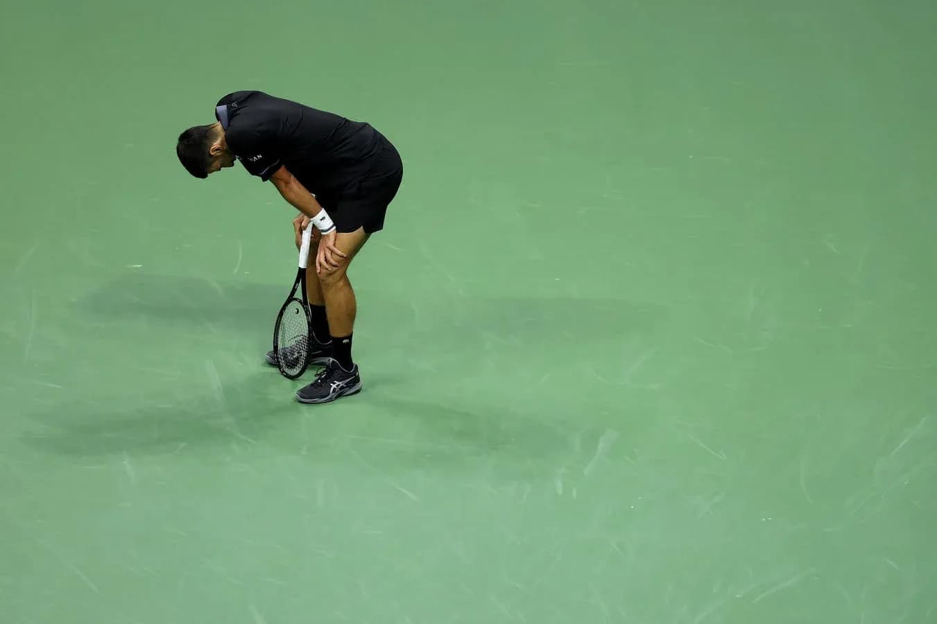 Jugador de tenis agachado sosteniendo su raqueta Jugador de tenis agachado sosteniendo su raqueta